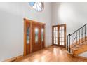 Bright foyer with hardwood floors, a large front door and a staircase leading upstairs at 102 Staghorn Way, Franktown, CO 80116