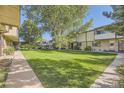 Well-maintained townhome featuring mature trees and a lush green lawn at 1847 Quail St # 10, Lakewood, CO 80215