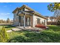 Rear exterior showing covered porch, well-maintained lawn, garden area, brick accents, and partial view of neighboring house at 6500 E Asbury Ave, Denver, CO 80224