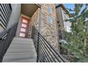 A beautifully designed entrance with stone accents and a modern red door, complemented by sleek black railings at 2602 Meadows Blvd # A, Castle Rock, CO 80109