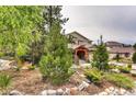 Landscaped front yard with a variety of trees, shrubs, and decorative rocks, providing a natural setting at 1970 Woodbourne Ter, Castle Rock, CO 80104