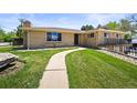 Inviting single-story home featuring a lush green lawn and curved walkway to the front door at 2704 S Ames Way, Denver, CO 80227