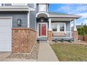 Inviting front porch with brick columns, a white railing, and a bright red front door at 4235 Lark Sparrow St, Highlands Ranch, CO 80126