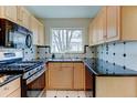 Well-lit kitchen featuring stainless steel appliances, maple cabinets, and black countertops at 4078 Ames St, Wheat Ridge, CO 80212
