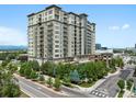 Modern high-rise apartment building with multiple balconies, landscaping, and adjacent city street at 5455 Landmark Pl # 815, Greenwood Village, CO 80111