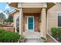Inviting front porch with colorful door, brick accents, and charming decor at 2164 S Troy Way, Aurora, CO 80014