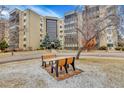 A serene view of a multi-story apartment building with mature trees and benches at 13631 E Marina Dr # 105, Aurora, CO 80014