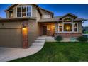 Beautiful residence showcasing a well-manicured lawn, brick accents, a two-car garage, and a cozy front entry at 12534 W Hoover Ave, Littleton, CO 80127
