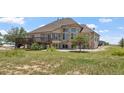 Expansive home exterior with large windows, a deck, and lush greenery at 34771 E 153Rd Ct, Hudson, CO 80642