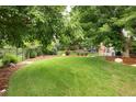 Expansive, fenced backyard featuring lush green grass and mature trees providing ample shade at 8783 E Phillips Pl, Centennial, CO 80112