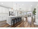 Open-concept kitchen featuring a large island with seating, modern pendant lighting, and wood-look floors at 17901 E Emilia Dr, Parker, CO 80134