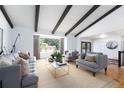 Spacious living room with exposed beams, neutral furniture, and large windows at 3843 S Quince St, Denver, CO 80237