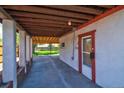 Covered carport featuring exposed wood beam ceiling and concrete flooring next to a doorway with white trim at 1560 Simms St, Lakewood, CO 80215