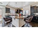 Modern kitchen with a granite island, dark cabinetry, pendant lighting, and stainless steel appliances at 23593 E Chenango Pl, Aurora, CO 80016