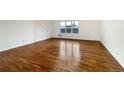The empty living room features newly refinished hardwood floors, neutral paint, and a large window at 12375 Ivy Pl, Brighton, CO 80602