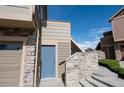 Townhome entrance features a stylish blue door, stone accents, and convenient access to the attached garage at 5732 S Addison Way # E, Aurora, CO 80016