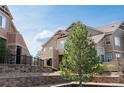 Exterior of townhomes showcasing meticulous landscaping, including mature trees and retaining walls, enhancing curb appeal at 5732 S Addison Way # E, Aurora, CO 80016