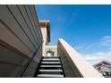 Stairway leading to upper level, highlighted by neutral siding and a clear blue sky backdrop at 5732 S Addison Way # E, Aurora, CO 80016