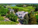 Breathtaking aerial view of a white home on a golf course, lush trees, and a lake at 96 Glenmoor Ln, Cherry Hills Village, CO 80113
