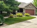 Landscaped front yard featuring a lush lawn, mature trees, and flowering bushes enhance the home's curb appeal at 5810 Moss Ct, Golden, CO 80403