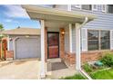 Inviting front entrance featuring brick accents, covered porch, and gray garage door at 5275 Cody St, Arvada, CO 80002