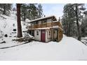 A unique home with a stylish deck, wood railings, and a snow-covered wooded setting at 11710 Spruce Canyon Cir, Golden, CO 80403