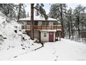 Cozy home nestled in a snowy, wooded landscape with a charming deck and unique wood railings at 11710 Spruce Canyon Cir, Golden, CO 80403