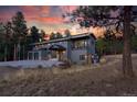 Gray modern home nestled in trees with a deer in the foreground at 1580 Crystal Way, Franktown, CO 80116