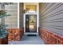 View of front door with security door, brick trim, and gray siding at 16123 Quarry Hill Dr, Parker, CO 80134
