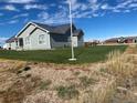 Expansive backyard view featuring a lush lawn, mature trees, and a charming grey house at 51 W 6Th Pl, Byers, CO 80103