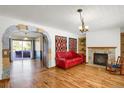Inviting living room with stone fireplace, hardwood floors, and archway leading to outdoor space at 3619 Estates Cir, Larkspur, CO 80118