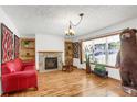 Cozy living room with a stone fireplace, hardwood floors, built-in shelving and natural light at 3619 Estates Cir, Larkspur, CO 80118
