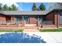 Welcoming brick porch with iron railings and manicured flower beds at 4031 S Hudson Way, Cherry Hills Village, CO 80113