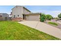 Home exterior featuring a two-car garage, brick accents, and lush green lawn at 12651 Elm St, Thornton, CO 80241