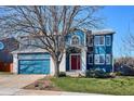 Charming two-story home featuring a red door, blue siding, an attached garage, and a well-maintained lawn at 4175 S Andes St, Aurora, CO 80013
