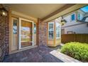 Inviting front porch featuring brick accents, decorative windows, a wooden front door, and manicured landscaping at 5416 S Hannibal Ct, Centennial, CO 80015