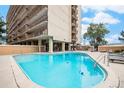Outdoor swimming pool with lounge chairs at the University Park Tower with a clear blue sky and beautiful trees at 2225 Buchtel Blvd # 208, Denver, CO 80210