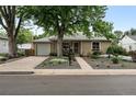 Inviting single-story home featuring a landscaped front yard, attached garage, and cozy front porch at 2925 S Harrison St, Denver, CO 80210