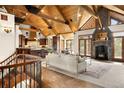 Spacious living room featuring a stone fireplace, wood-beamed ceilings, and seamless flow to the kitchen at 7115 Parkwood Ln, Castle Pines, CO 80108