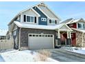 Beautiful two-story home with stone accents, a covered front porch, and a gray two car garage, set in a snowy neighborhood at 1048 Larkspur Dr, Erie, CO 80516