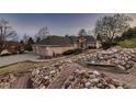 Expansive home showcasing brick and stone details, plus a mature landscape and walkway to the front door at 7769 W 70Th Dr, Arvada, CO 80004