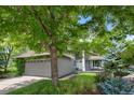 Beautiful home featuring an inviting front porch and a well-manicured lawn, framed by mature trees and blue spruce at 12 Long Spur, Littleton, CO 80127