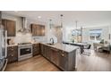 Open-concept kitchen featuring stainless steel appliances, wooden cabinetry, granite counters, and hardwood floors at 1640 Winona Ct, Denver, CO 80204