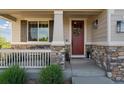 Inviting front porch with stone accents, decorative shutters, and a charming red front door at 3741 Harvard Pl, Broomfield, CO 80023