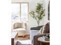 Bright living room with a faux tree by a window, a comfortable white chair and an area rug at 6580 Independence Way, Arvada, CO 80004