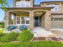 Charming home entrance showcasing a stone-accented porch with decorative pillars, landscaping and a solid front door at 1648 Exquisite St, Castle Rock, CO 80109