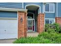 Welcoming front entrance with brick columns, an ornate storm door, and lush landscaping at 19113 W 60Th Ln, Golden, CO 80403