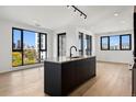 Modern kitchen with dark island, stainless appliances, and beautiful hardwood floors at 1601 Park Ave # 506, Denver, CO 80218