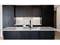 Contemporary kitchen featuring dark cabinets and an island with stone countertops and a black faucet at 1601 Park Ave # 506, Denver, CO 80218
