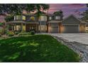 Charming two-story home boasts a well-manicured lawn, a three-car garage, and attractive brick accents at sunset at 4541 Christensen Cir, Littleton, CO 80123